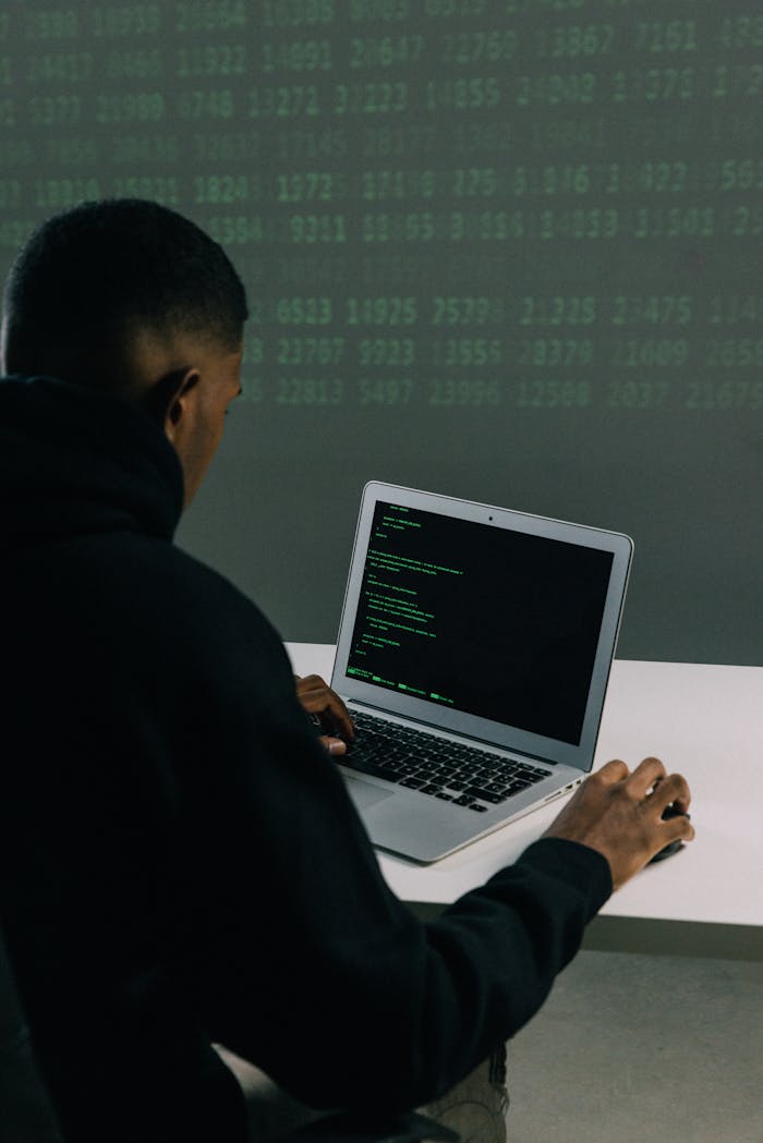 about-img A programmer engaged in coding on a laptop in a tech-focused workspace with a digital interface.